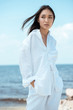 © LIGHTFIELD STUDIOS - attractive young asian woman with hands in pockets looking away on beach
