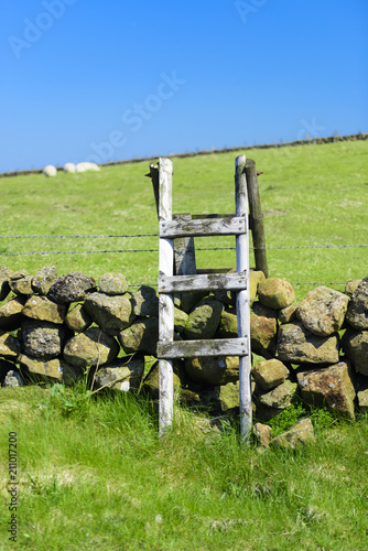 Fotografie, Obraz A wooden stile over a dry stone wall and barbed wire, County Antrim, Northern Ireland