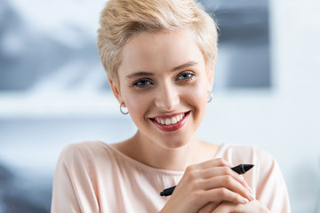 close up portrait of smiling attractive woman holding pen for graphic tablet