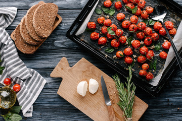 Wall Mural - Pan with baked tomatoes and pieces of cheese and bread on dark wooden table