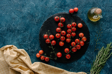 Wall Mural - Dark slate board with cherry tomatoes and oil bottle on blue table