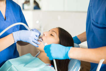 Wall Mural - Medical Team Examining Girl With Dental Equipment At Clinic