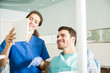 © AntonioDiaz - Smiling Dentist And Patient Looking At Digital Tablet In Clinic