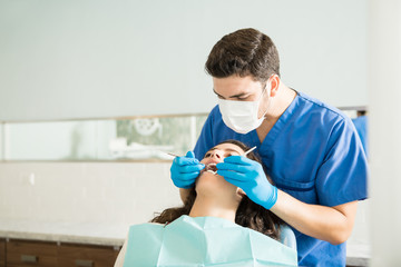 Wall Mural - Dentist Examining Woman With Dental Carver At Clinic