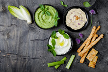 Green Vegetables Raw Snack Board With Various Dips. Yogurt Sauce Or Labneh, Hummus, Herb Hummus Or Pesto With Crackers, Grissini Bread And Fresh Vegetables. Middle Eastern Meze Snacks Set