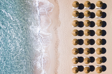 Wall Mural - Aerial view of amazing turquoise sea with brown straw umbrellas and sun loungers. Beautiful sunny summer day in Sardinia, Mediterranean sea, Italy..