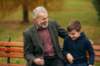 © Aleksandr - Grandpa and his grandson spend time together in the park. They are sitting on the bench. Walking in the park and rejoicing