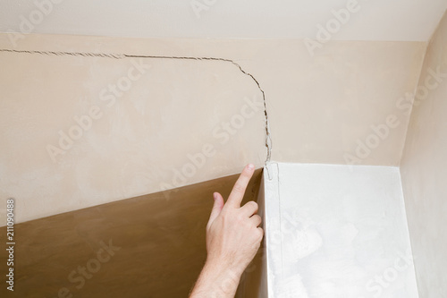 Fotografía Man's hand finger pointing to the cracked wall in house