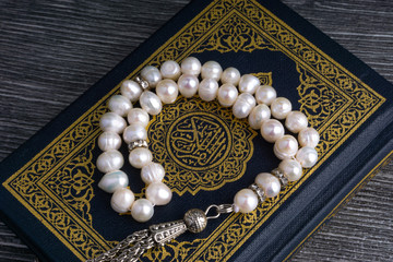 Poster - Kuala Lumpur, Malaysia- December 4, 2017: Closeup of Holy Quran/Koran with beads or Tasbih/Rosary over wooden background.Selective focus and crop fragment.