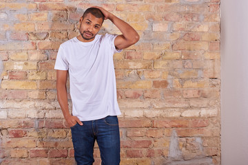 Portrait of a serious handsome young man in a white tshirt and blue jeans.