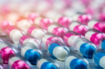 Wall Mural - Closeup pink-white and blue-white antibiotics capsule pills in blister pack. Antimicrobial drug resistance. Pharmaceutical industry. Global healthcare. Pharmacy background. Amoxicillin capsule pills.