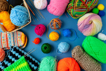 Yarn And Knitting Needles On A Blue Background. A Lot Of Colorful Yarn Is Folded Into A Frame On A Blue Background. Knitting As A Kind Of Needlework.