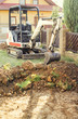 Mini excavator on construction site. Excavator regulates the terrain around the house. Digger digging soil