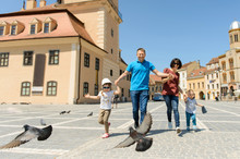 Family Running With Flying Pigeons In Street