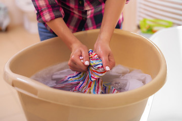 Women's hands wash clothes in the basin.