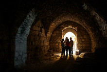 KERAK, JORDAN - Nov 2009: A Small Group Of Tourists Stand In A Dark Chamber, Silhouetted By Glowing Sunlight Through An Archway Window Inside The Ancient Crusader Castle At Karak Near Amman In Jordan