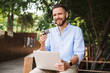 Smiling emotional young bearded man using laptop