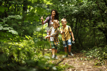 mother and her little sons hiking trough forest .