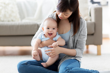 Wall Mural - family and motherhood concept - happy smiling young asian mother with little baby at home