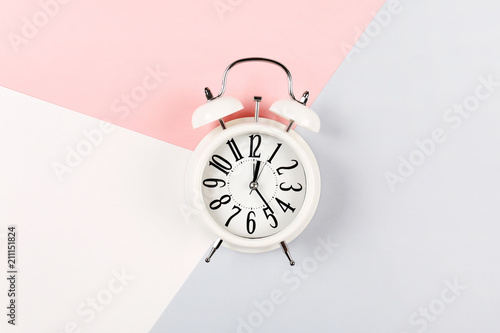 Fotomural White antique alarm clock on a three-color pink, gray and white background