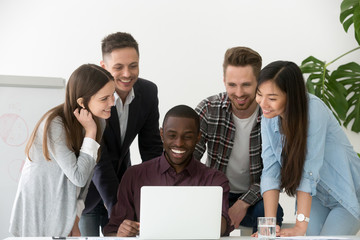 Poster - Smiling diverse work team feeling excited reading good online news at laptop on company business success, colleagues happy with online win, shared goal achievement. Concept of cooperation, teamwork