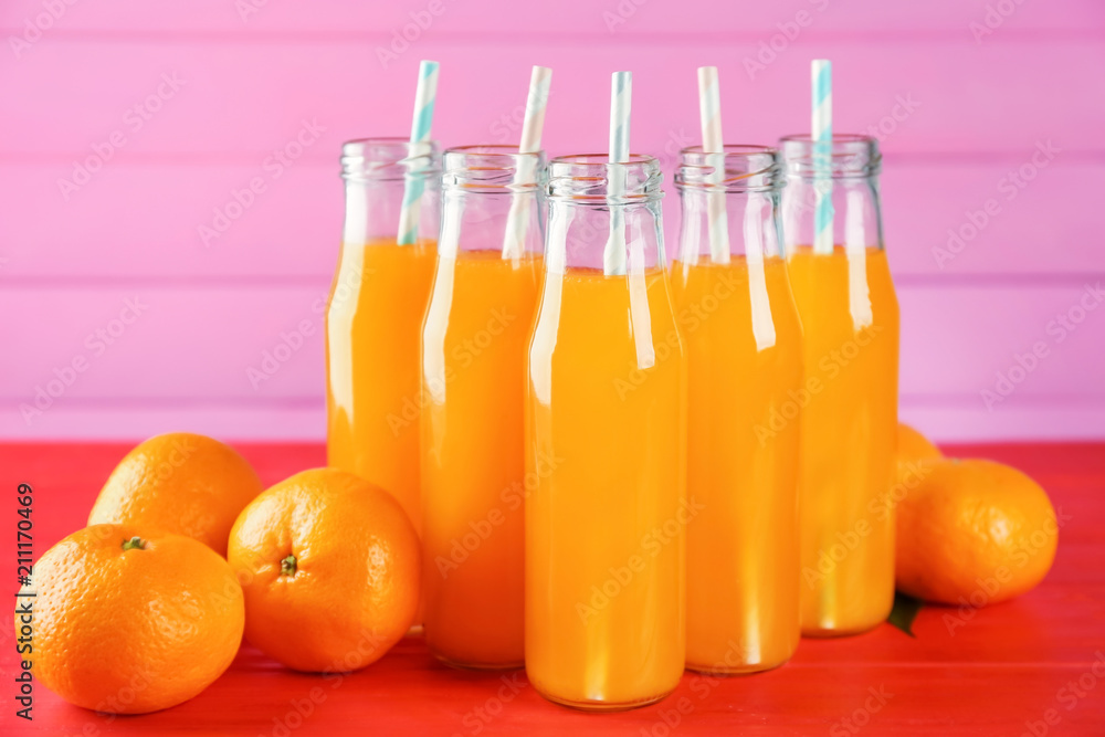 Bottles with fresh citrus juice and tangerines on table