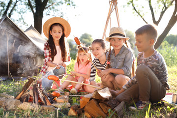 Poster - Little children frying sausages on bonfire. Summer camp