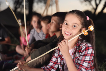 Wall Mural - little girl with fried marshmallows outdoors. summer camp