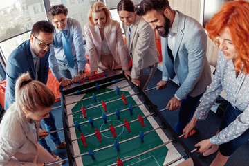 Poster - Smiling business colleagues playing table football