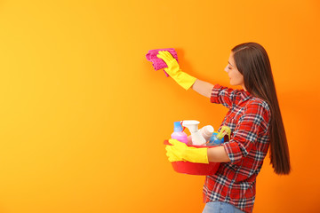 Canvas Print - Young woman cleaning color wall with rag