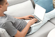 © New Africa - Man in casual clothes using laptop on sofa at home