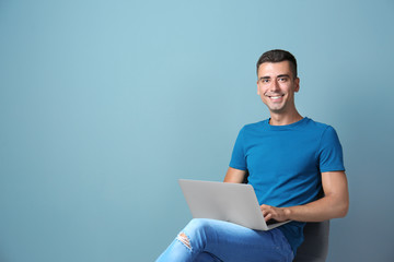 Man in casual clothes with laptop on color background