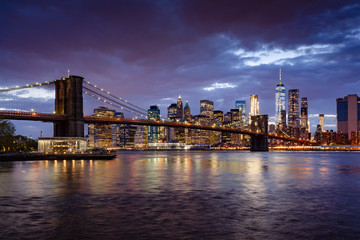 Fototapete - Brooklyn Bridge and illuminated Lower Manhattan skyscrapers at dusk with the East River. Manhattan, New York City
