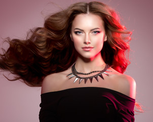 Woman high fashion model with luxurious long healthy, wavy, voluminous hair in colorful bright lights.