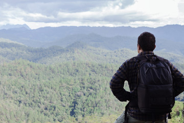 Wall Mural - young man whit backpack on top of the mountain looking to the forest