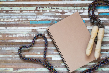 Poster - Flat lay top view of blank space notebook with skipping rope or jump rope in heart shaped on grunge wooden background