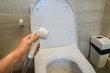 © jummie - close up woman hold rinse spray hose in toilet for cleaning