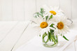Bouquet of daisies in vase on a wooden white table