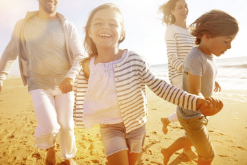 Wall Mural - Family running on sandy beach at sunset