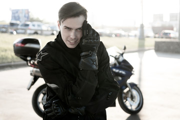 Wall Mural - A white young man is standing next to a motorcycle.