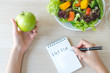 Dieting and calorie control for wellness. Woman calculate calories of food in breakfast during dieting for lose weight program and take notes.