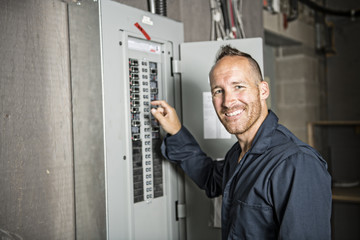 Man Technician servicing at work on electric room