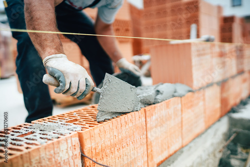 Fotografía Professional worker using pan knife for building brick walls with cement and mor