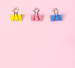 © gamjai - Colorful binder clips on pink background.