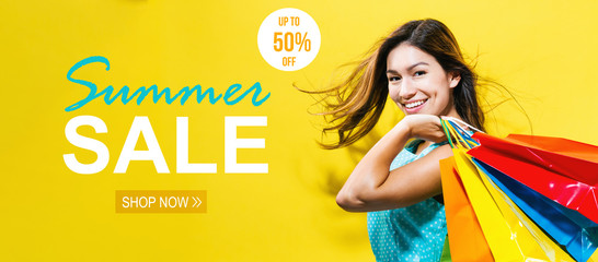 Wall Mural - Summer sale with happy young woman holding shopping bags on a yellow background