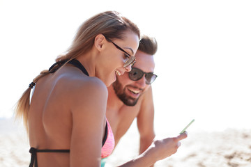 Smiling couple browsing their photos on the beach