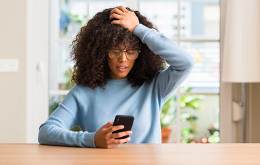 Sticker - Beautiful african american woman using smartphone stressed with hand on head, shocked with shame and surprise face, angry and frustrated. Fear and upset for mistake.