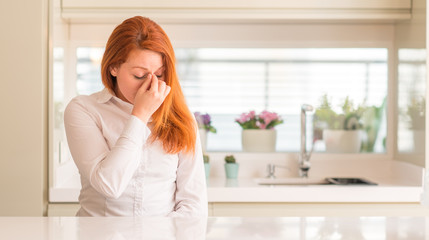 Sticker - Redhead woman at kitchen tired rubbing nose and eyes feeling fatigue and headache. Stress and frustration concept.