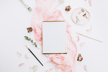 Wall Mural - Creative festive composition with photo frame mock up, pink blanket, flowers, eucalyptus branches and brushes on white background. Flat lay, top view stylish template.