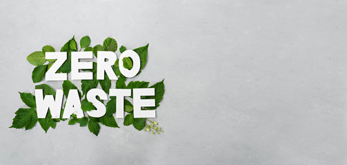 zero waste paper text witj green leaves on gray background